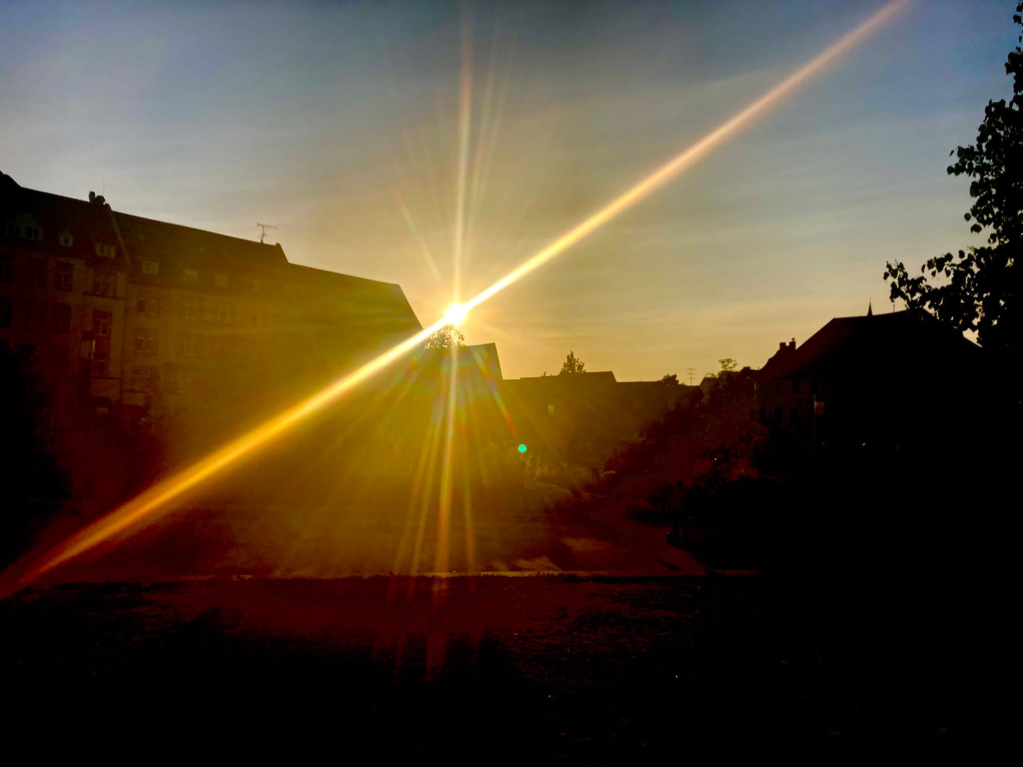 Die Sonne möchte langsam untergehen, Häuserzeilen schwarz.